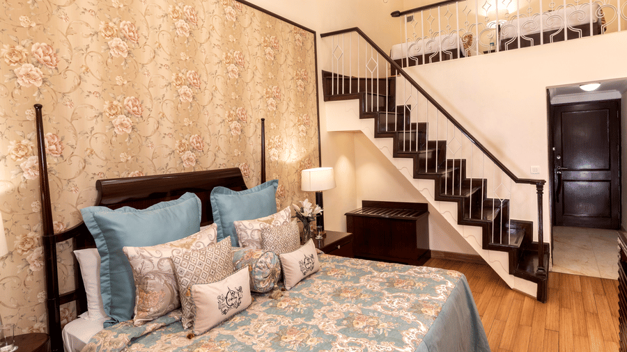 image of a king size bed with a staircase going up at Duplex Family Suite at The Claridges Nabha Residence