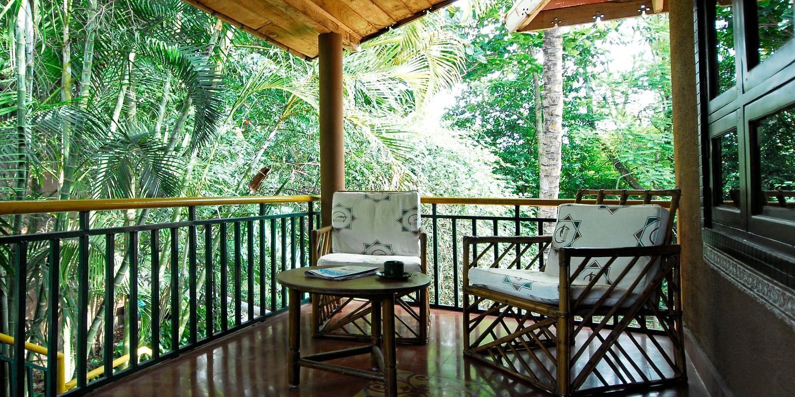 image of the outdoor seating area with lush green surroundings at the heritage premium rooms at hoysala village resort, hassan.