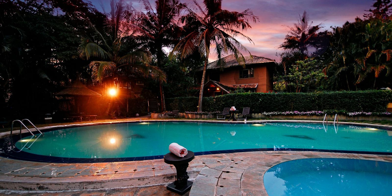 An overview of a swimming pool in the night - Hoysala Village Resort, Hassan.