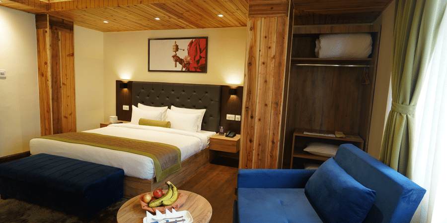 Bedroom with a bed, sofa seating, and wooden furnishings.