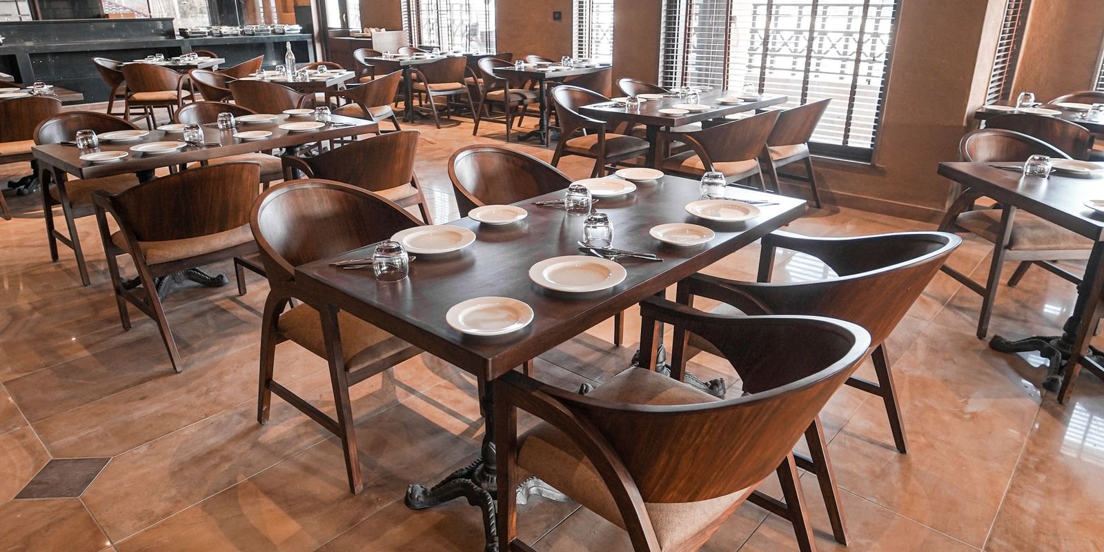  A spacious restaurant interior with many tables and chairs, ready for dining at Aamaghati Wildlife Resort.