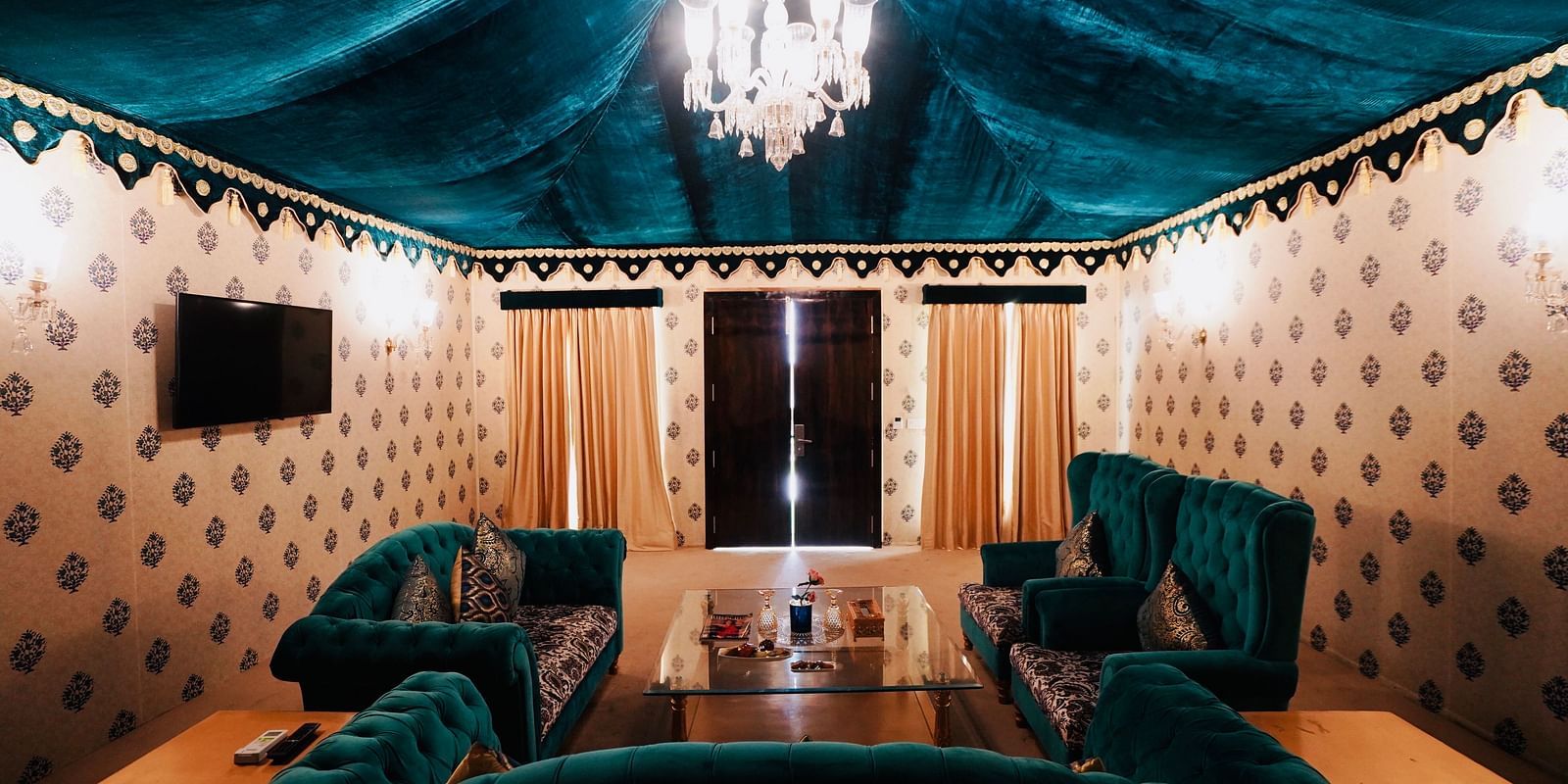 Image of a room with sofas and a table in between with a chandelier hanging from the ceiling at Rajasthali Resort & Spa Jaipur. 