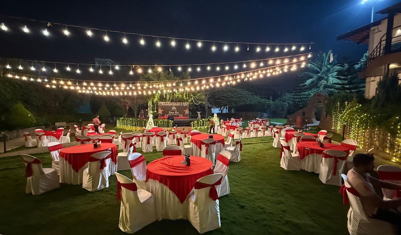 Outdoor lawn dining setup with string lights at Nirantara Resort.