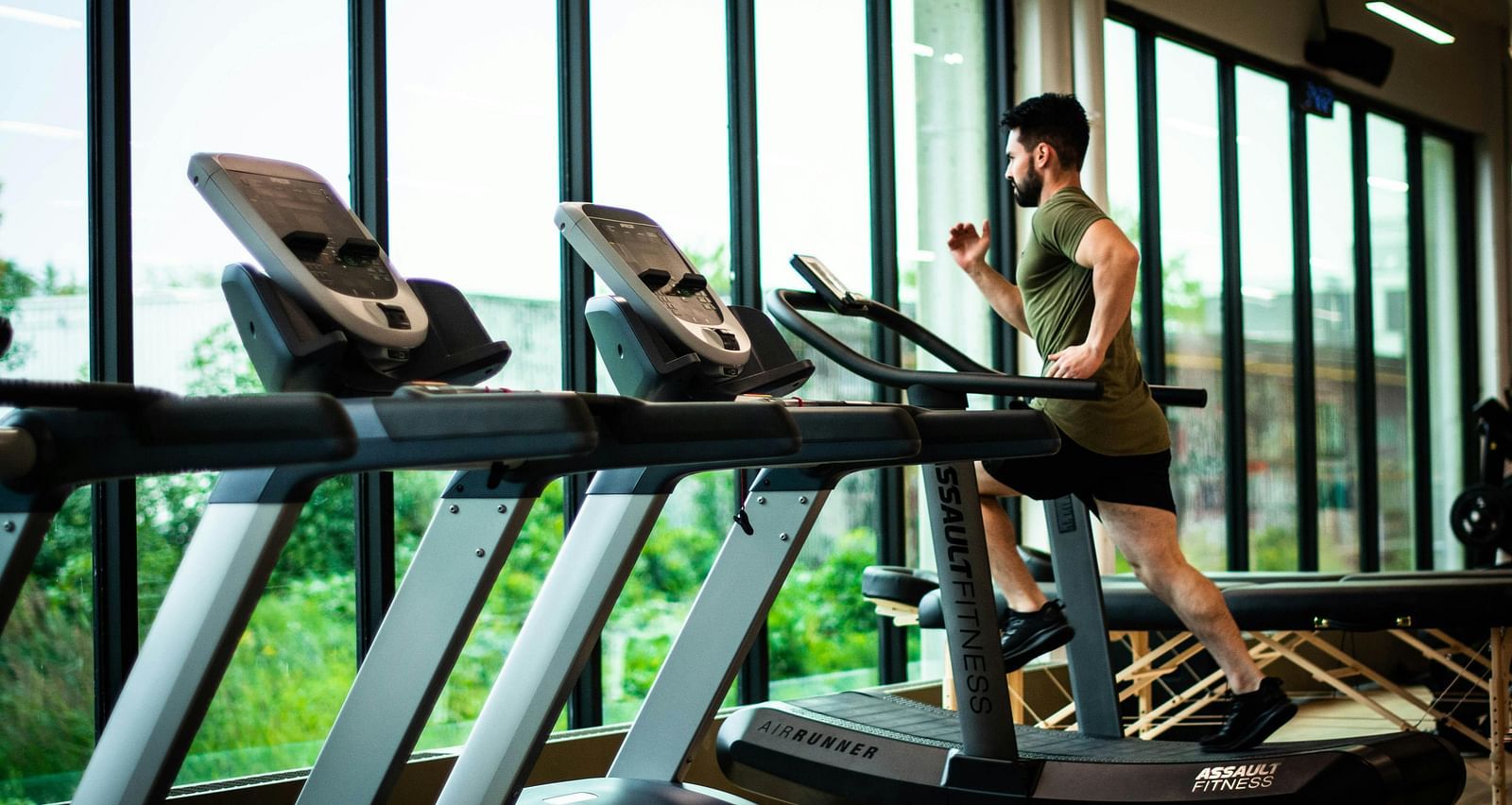 a person running on a treadmill as he looks outside to the serene green views