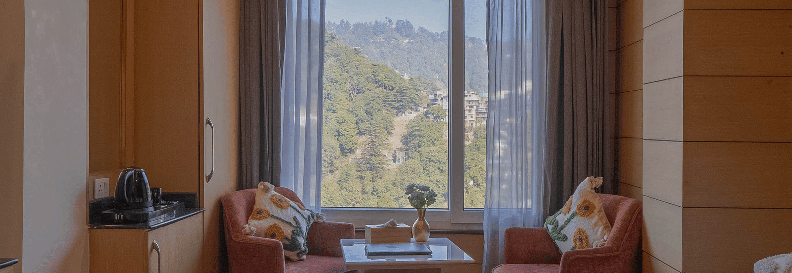 A seating area with chairs, table, and window view at Perfectstayz Premium at Mall Road Hotel Super, Mussoorie.