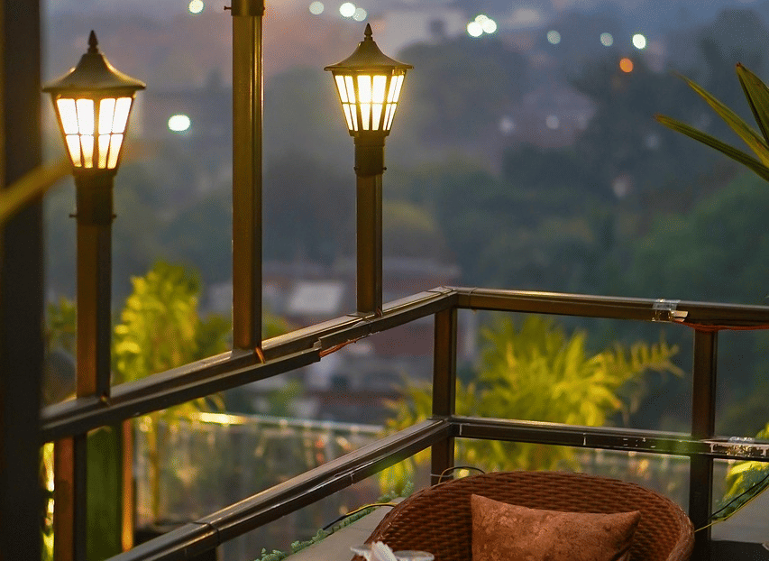 2 chairs facing each other on a terrace with warm lights beside it on a late evening.