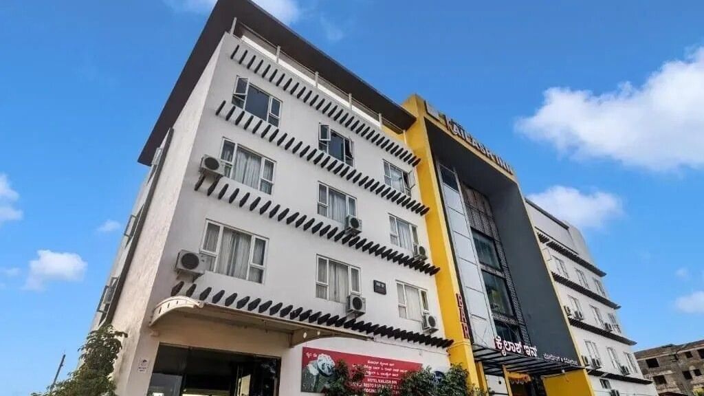 The exterior of a modern multi-story hotel building with yellow and grey accents under a blue sky - VITS Select Kailash Inn, Bagalkot