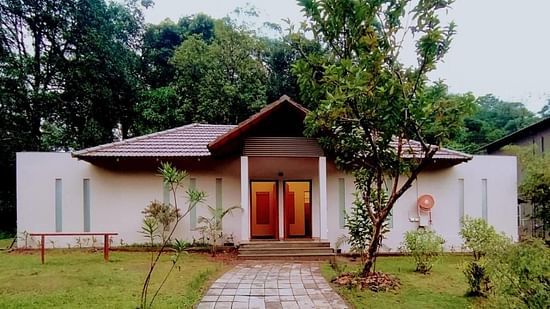 The exterior view of a villa shows a garden and a pathway leading to the entrance. - Abad Brookside Lakkidi, Wayanad