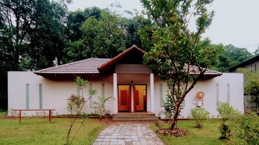 A house with a stone pathway is surrounded by a garden, showcasing its exterior.- Abad Brookside Lakkidi, Wayanad