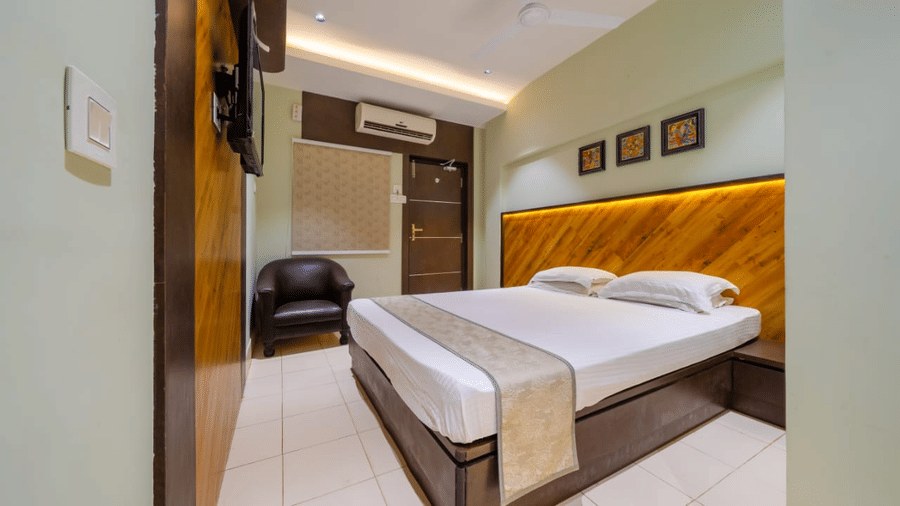 Spacious bedroom with a double bed, wall arts, an A/C, a seating area, and modern lighting – Hotel Dolphin Puri