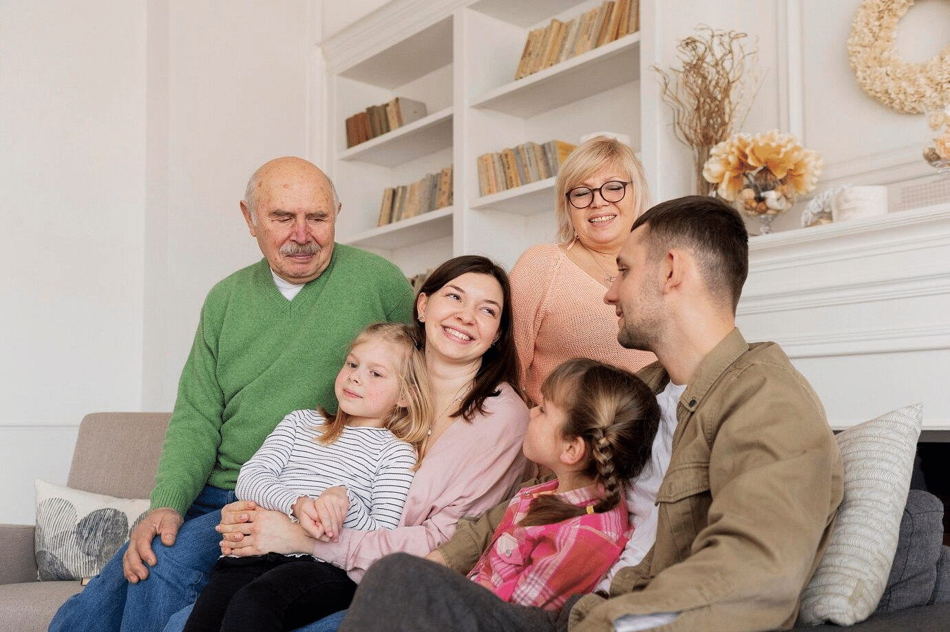 A group of people laughing at each other , with a background of a mounted shelf.