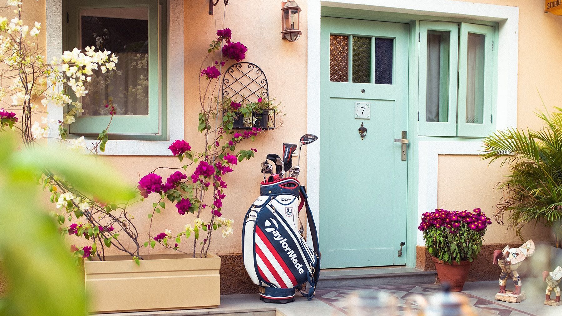 The entrance door to a unit at Karma Chalets with potted plants and a golf bag outside.