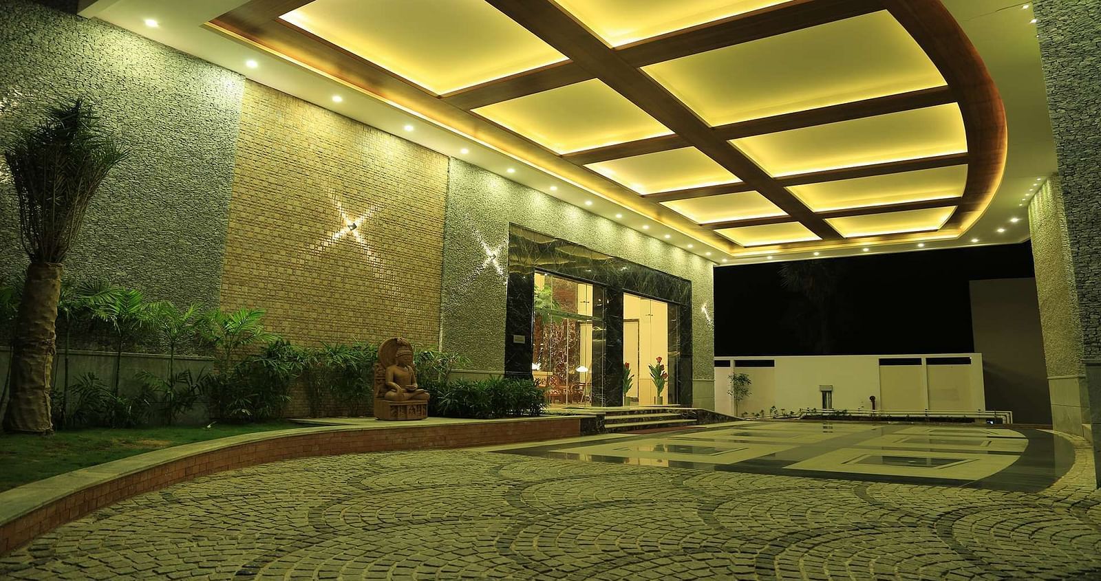 Well-lit entrance of Dhanalaksmi Srinivasan Hotels, Perambanur with a pathway leading to the door.