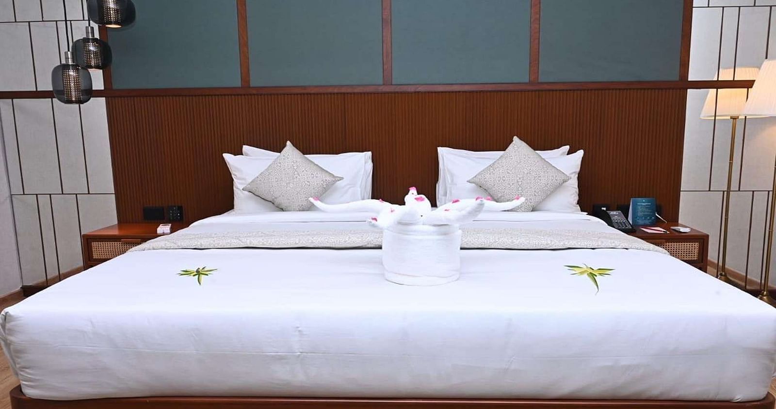 Close up of a Executive Suite at Dhanalakshmi Srinivasan Hotels, Perambalur featuring a bed with white linens, and dark wood headboard