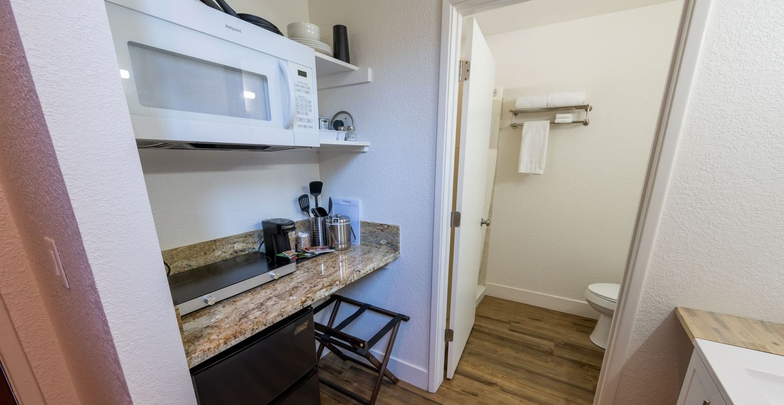 Deluxe King Room at Amador Hotel with kitchenette area including microwave, counter space, storage, and view into the bathroom.