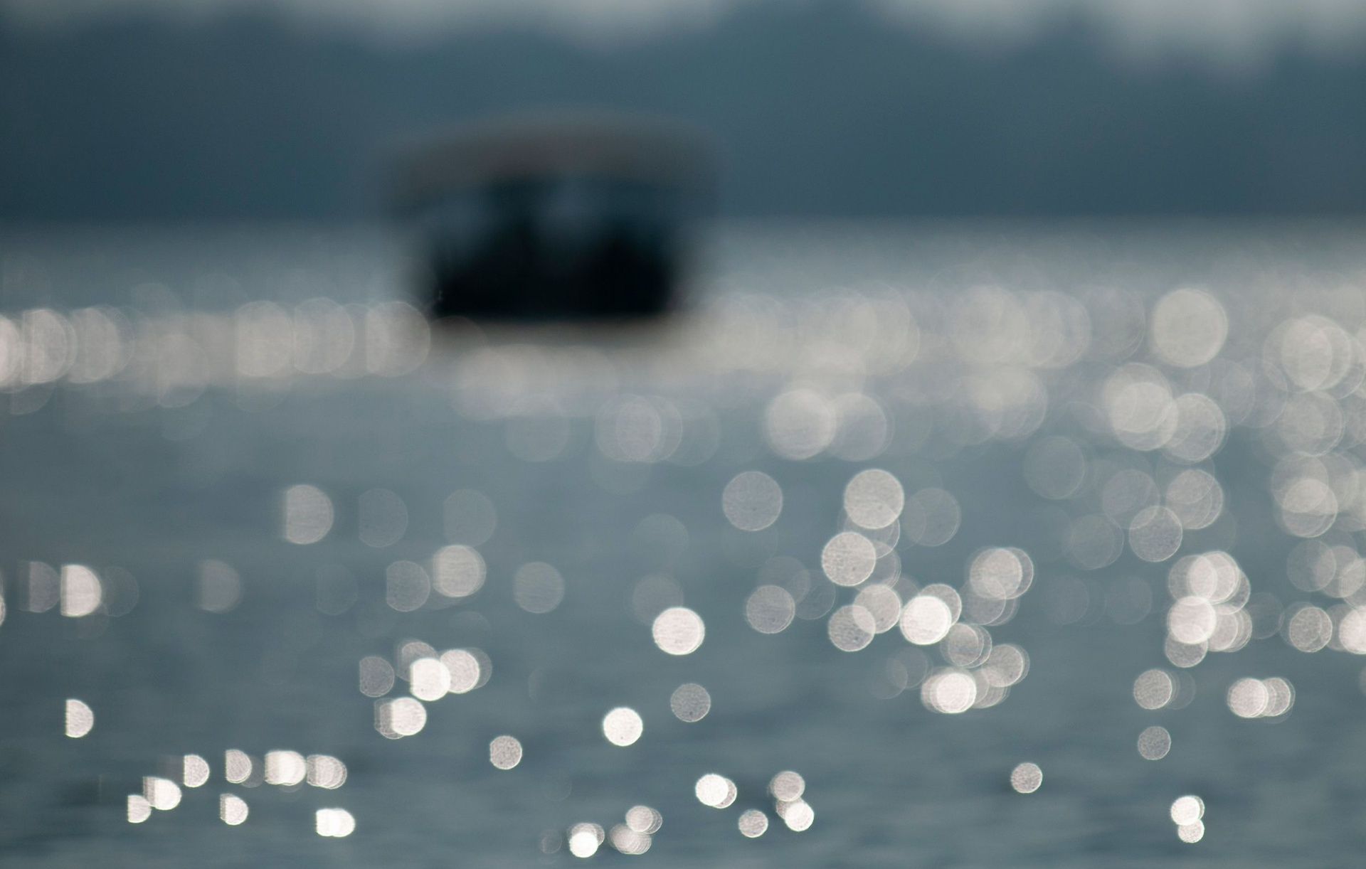 Glistening water with bokeh and a blurred boat.