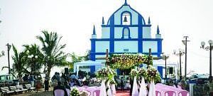 A church during the day adorned with a wedding setup featuring a red carpet and decorated chairs leading to the chapel entrance.