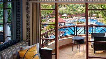 a sofa next to the balcony door inside one of the rooms - Caravela Beach Resort Goa