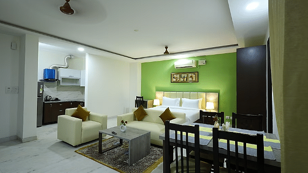 A hotel suite with a green accent wall, living area, dining table and an open kitchenette - Lime Tree Golf View, Golf Course Road