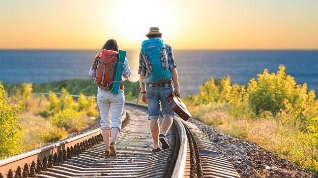 Two travellers walking on a railway line with the sun in front of them
