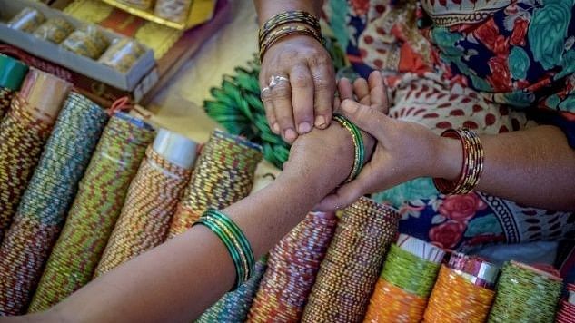 A close up shot of a woman putting bangles on the other woman hand