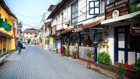 Cobbled street lined with colonial-style houses, balconies, and flower pots in Fort Kochi.