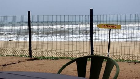 An image of a chair and a table with the backdrop of a beach where waves are hitting the shore