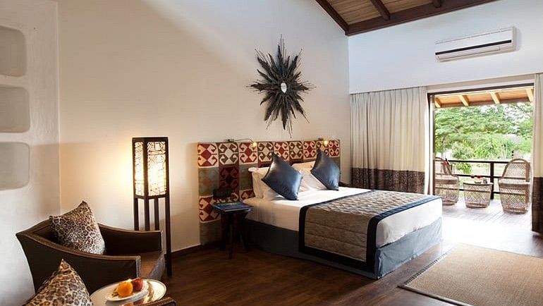 view of the sofas, bed and balcony in one of our rooms in Bandipur