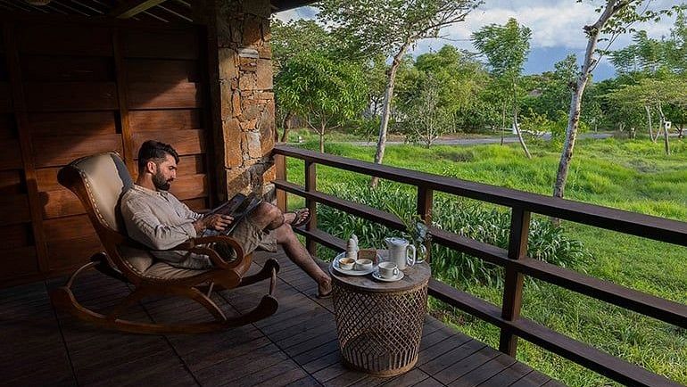 person reading on the balcony of one of our rooms in Bandipur