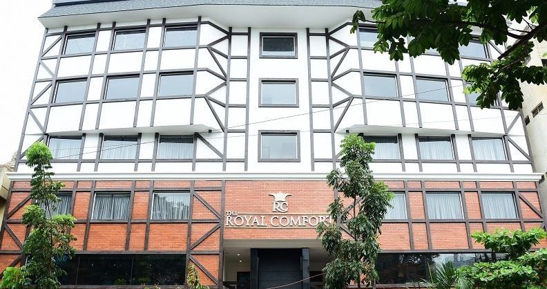 The modern, geometric-patterned exterior facade of The Royal Comfort hotel building, with orange and white panelling and a large, dark window.