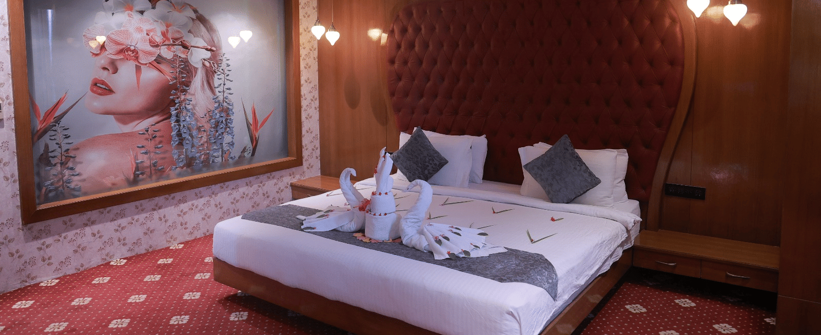 Sky Suite king bed with swan towel art, a tufted red headboard and a large floral portrait artwork