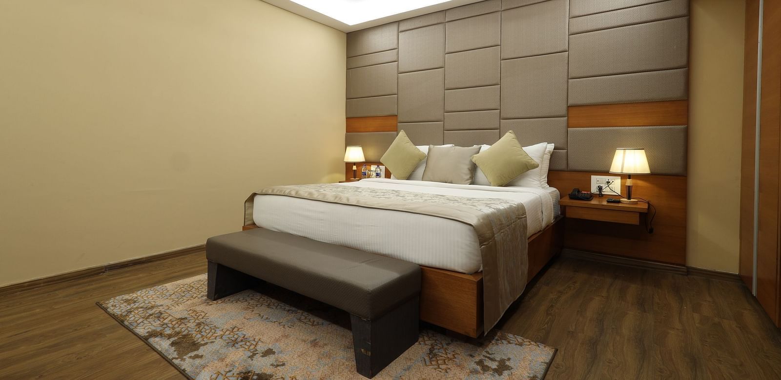 Hotel room interior with a bed, a bench, and a fan, a guest accommodation at Rang Lords Inn Bharuch