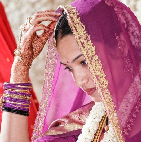 Indian bride adjusting her veil, hands with mehndi.