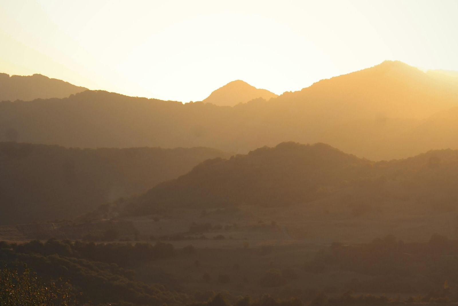 View of rolling mountains shadowed by a bright sun.