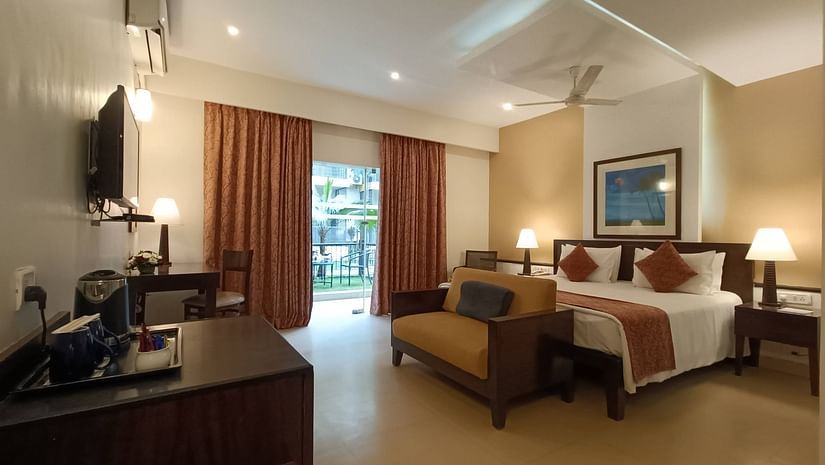 Image of Studio Room with Garden, showcasing a wall-mounted TV unit and a door leading to the balcony at Kyriad Prestige Calangute, Goa