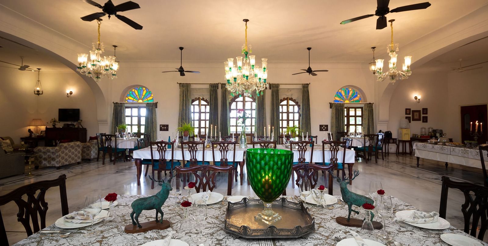 image showcaing the Indoor dining arrangement at Dev Shree, Deogarh with elegant chandeliers hanging from the top
