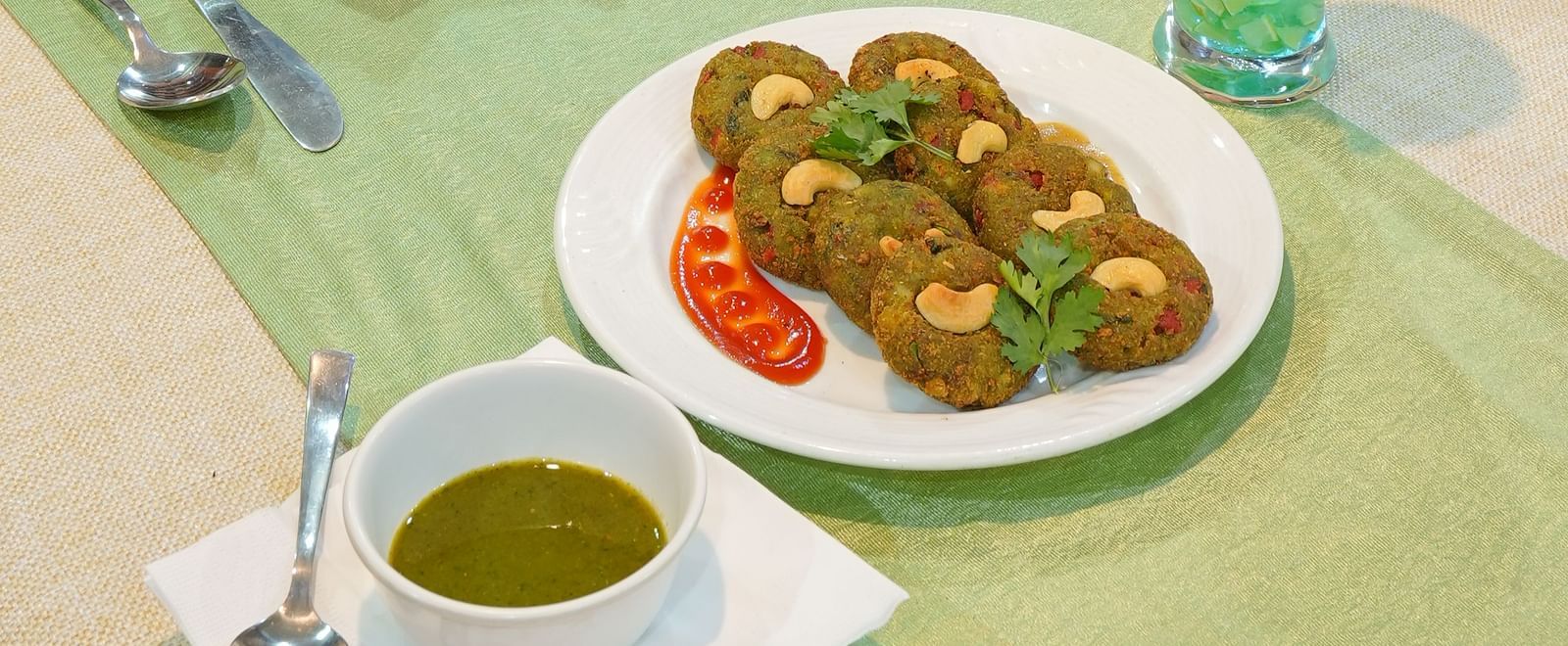 Dining table with decorated cloth, pea crisp patty, and a refreshing drink at DLS Hotels The Rock Castle.