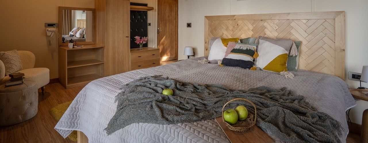 An image of a bedroom with king size bed, frames on the wall, a dressing table, a cabinet at Avalon Cottages, Kanatal