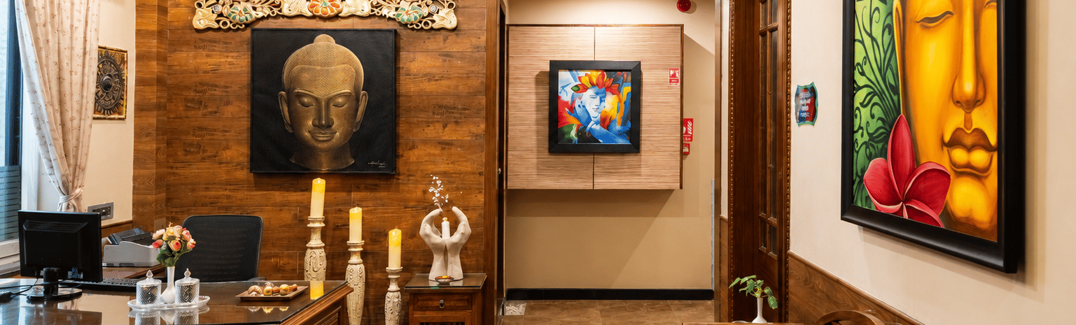Spa reception with a wooden desk, Buddha paintings, carved wall panel, tall candle stands and a wooden bench at MAYFAIR Palm Beach Resort, Gopalpur-on-Sea.