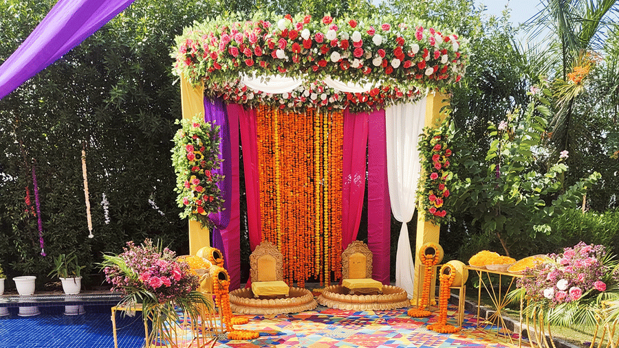 A poolside event setup at Corbett Nirvana Resort with a floral and draped archway and a vibrant, patterned carpet leading toward the pool.