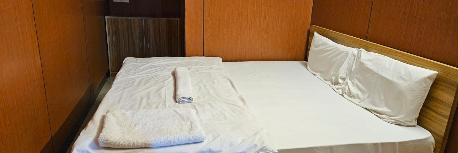 A double bed in a room featuring a window air-conditioner in the corner above a cabinet at the Dream Vision Guest House.