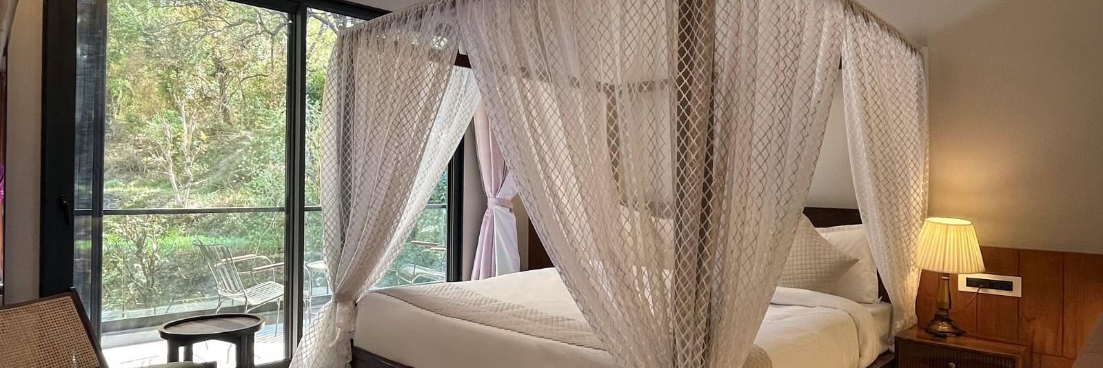 A hotel room with a beautiful bed with a glass door opening to the balcony - The Samai, Bhimtal