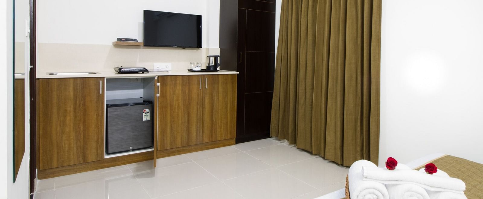 A hotel room showcasing a small kitchenette area and neatly folded white towels at Sanctum Suites Whitefield, Bangalore.