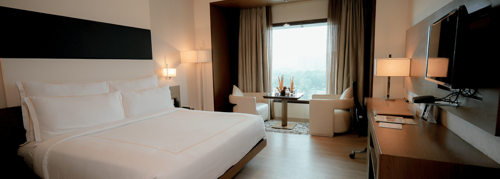 Deluxe room with king size bed and warm lighting at Narayani Heights Hotel & Resorts, Ahmedabad.