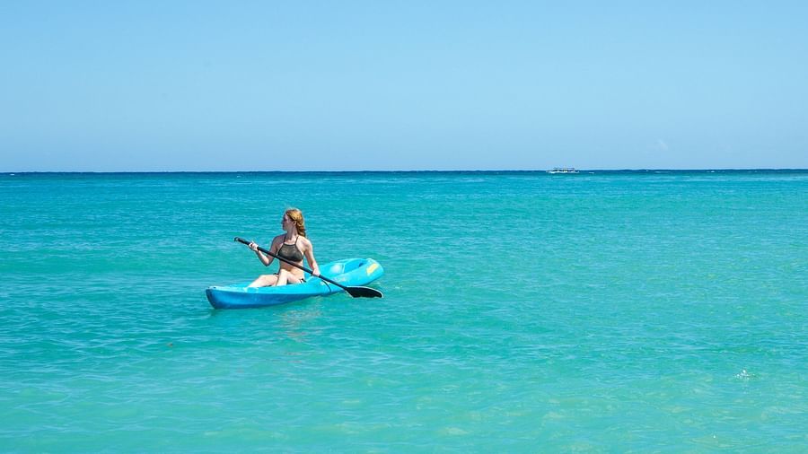 A person sitting on a paddleboard in the middle of clear blue waters, with a vast open horizon in the background | Abaco Inn