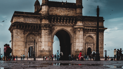 A view of Gateway of India from afar with the building's reflection on the pool of water in front of it, a must-visit on a Mumbai Sightseeing Tour