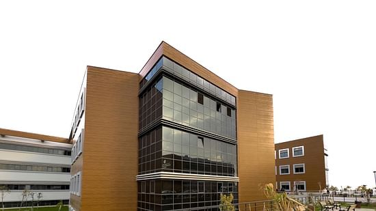 An image of a building surrounded by lawns where benches are placed