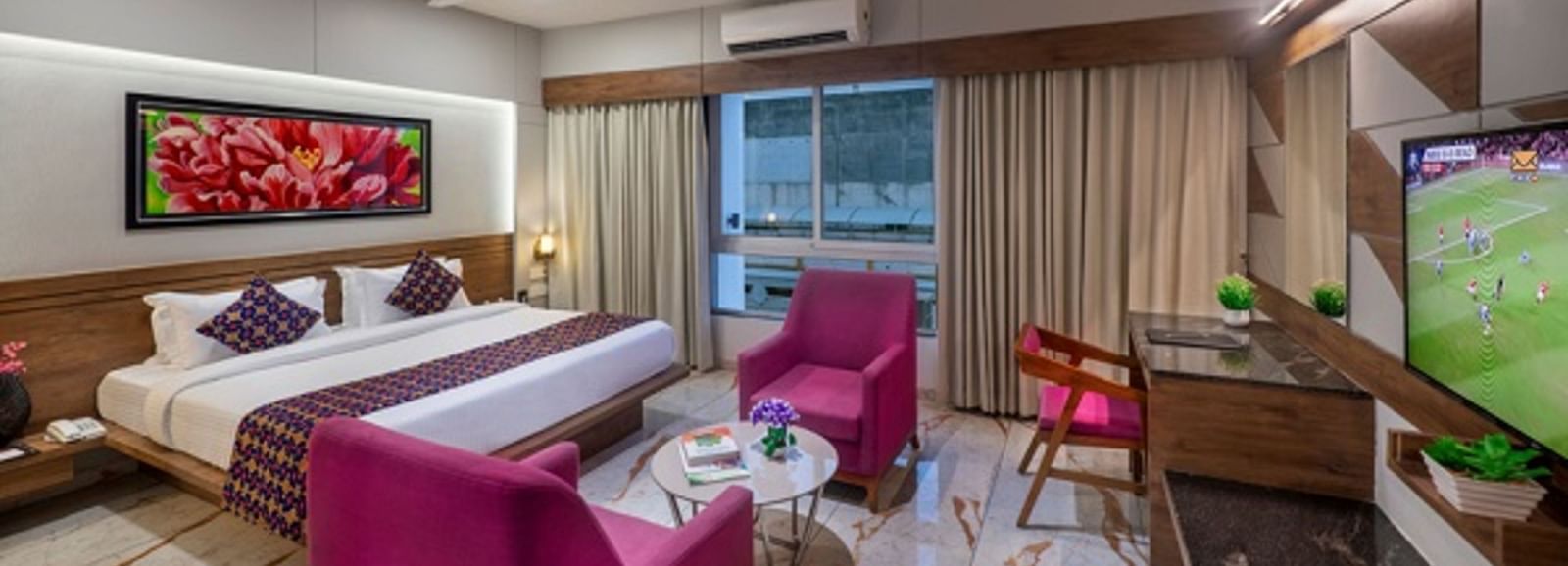 A room featuring a bed, a seating area with armchairs, and a television at Angel Lords Eco Inn Amreli.