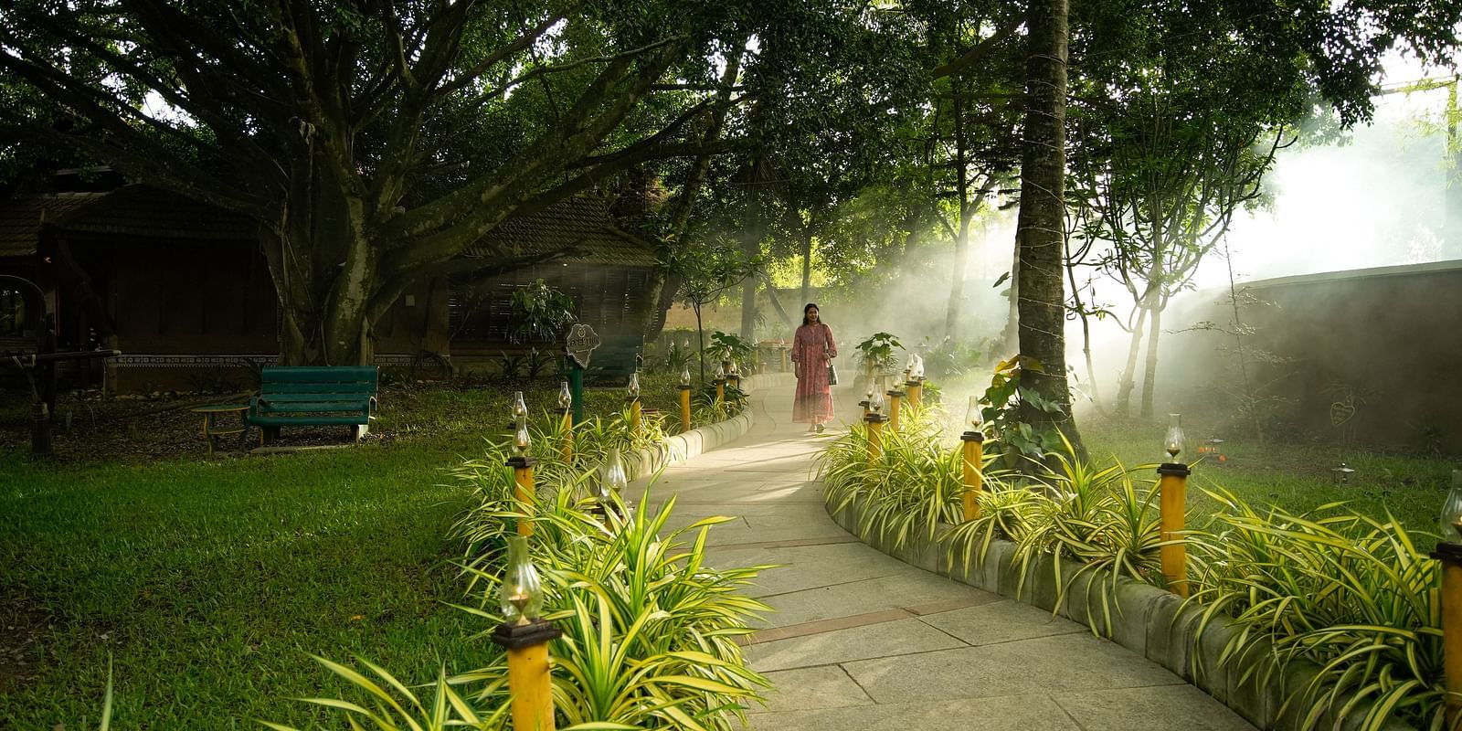 a pathway amidst the green garden at hoysala village resort, hassan