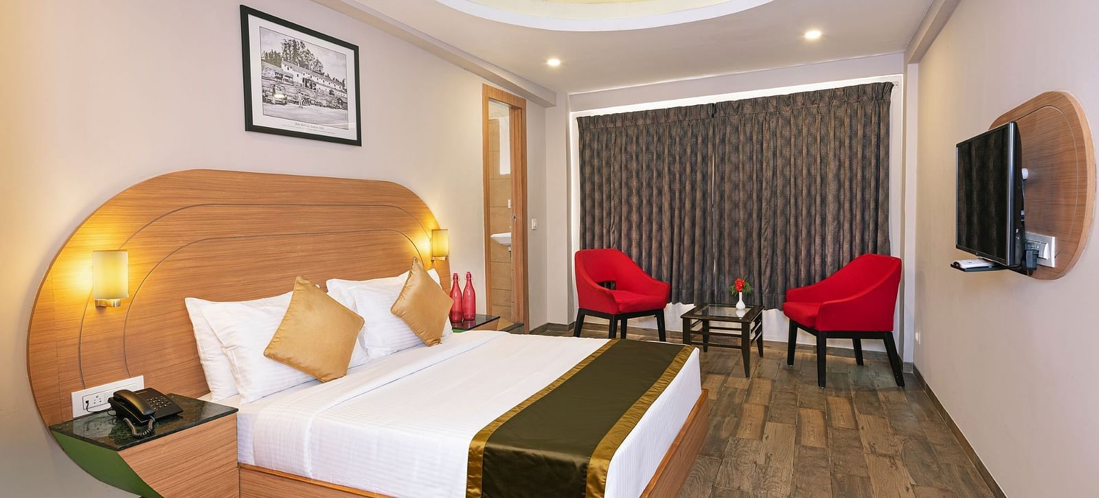 An image of a bedrom with dube sized bed and chairs on a different corner  | Mango HIll Central, Ooty